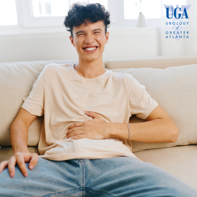 A happy man smiling while holding his abdomen after recovering from bladder trauma in Atlanta, Georgia.