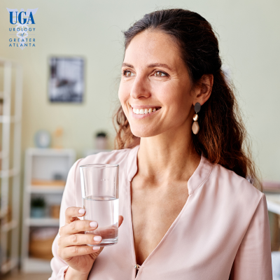 A woman drinking a glass of water to keep her bladder healthy.